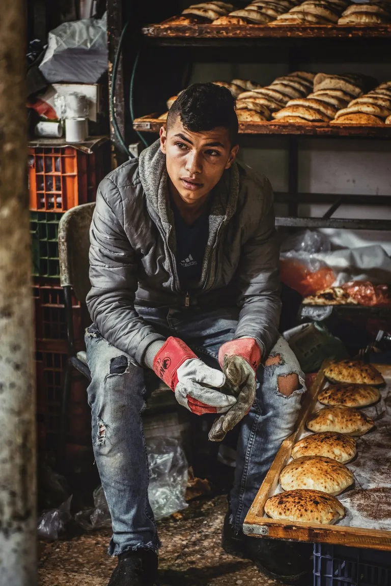 Un joven sentado cerca de varias bandejas con pan. | Foto: Pexels