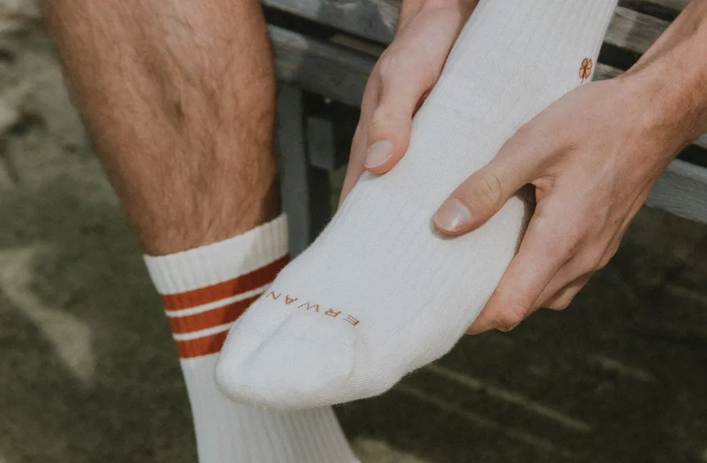 Una persona con calcetines blancos sosteniendo su pie. | Foto: Pexels
