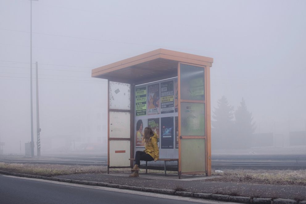 Una mujer sentada en una parada de autobuses. | Foto: Unsplash