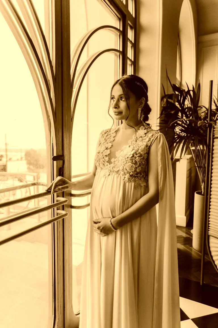 Una mujer embarazada mirando a través de un ventanal. | Foto: Pexels
