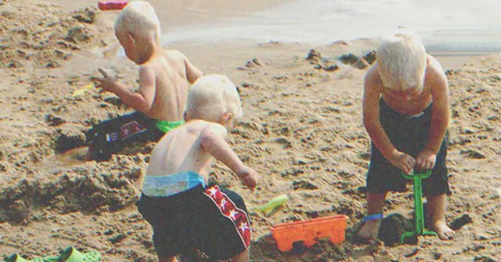 Trillizos jugando en la arena cerca de la playa. | Foto: Shutterstock