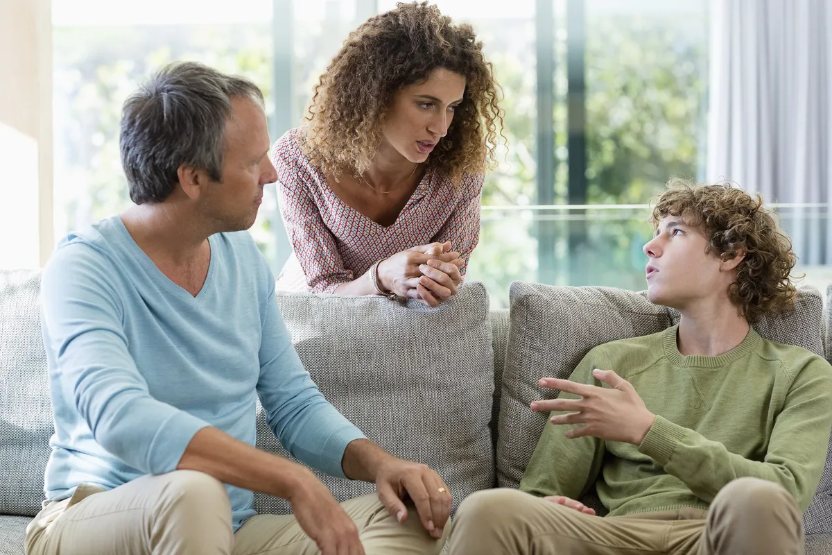 Padres hablan con su hijo adolescente en la sala de estar. | Foto: Getty Images 