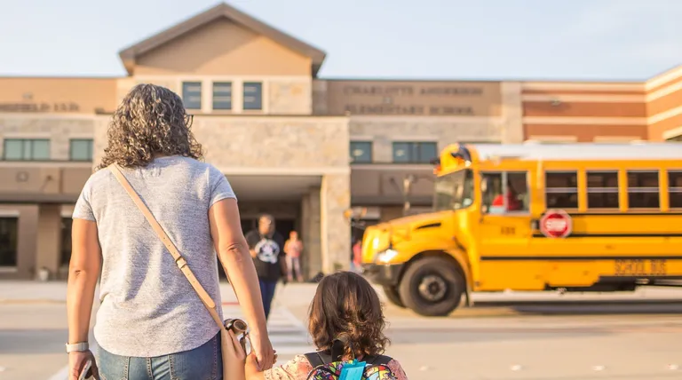 Una madre caminando junto a su hija pequeña hacia la escuela. | Foto: Pexels