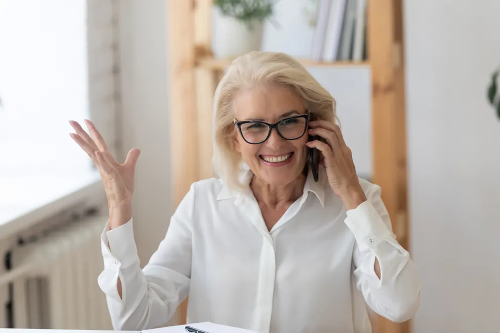 Femme âgée souriant tout en parlant au téléphone. │Source : Shutterstock