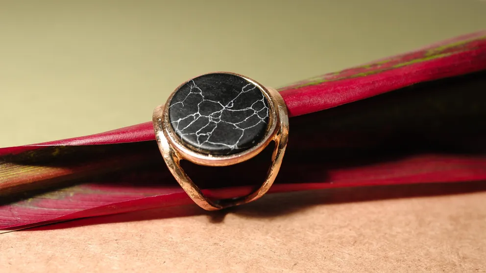 Un anillo dorado con una piedra plana de color negro. | Foto: Pexels