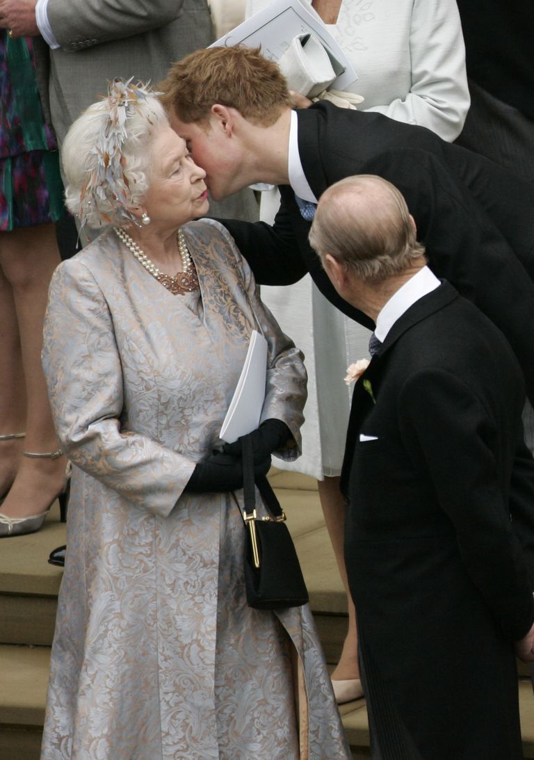 Le prince Harry photographié embrassant sa grand-mère la reine Elizabeth II après le mariage de Peter Phillips à Autumn Kelly, à la chapelle Saint-Georges du château de Windsor, le 17 mai 2008 à Windsor, en Angleterre. │ Source : Getty Images