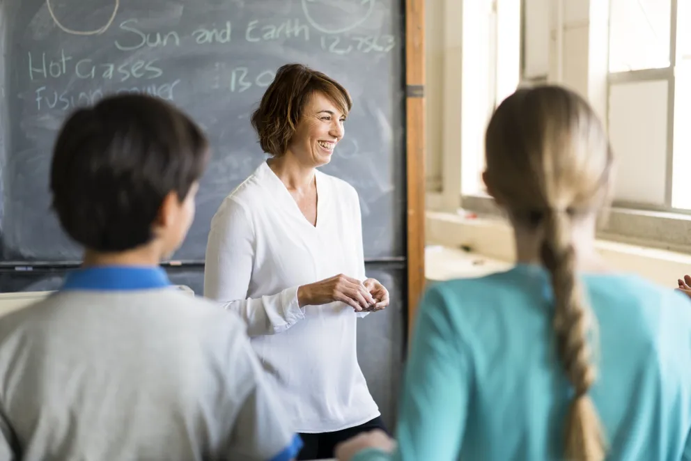 Mujer impartiendo clases en un aula a unos niños. | Foto: Getty Images