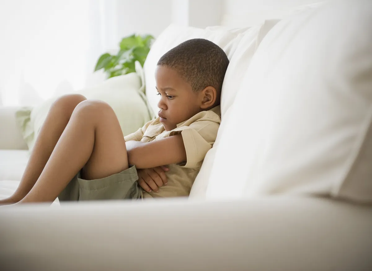Niño enojado con los brazos cruzados sentado en un sofá. | Foto: Getty Images