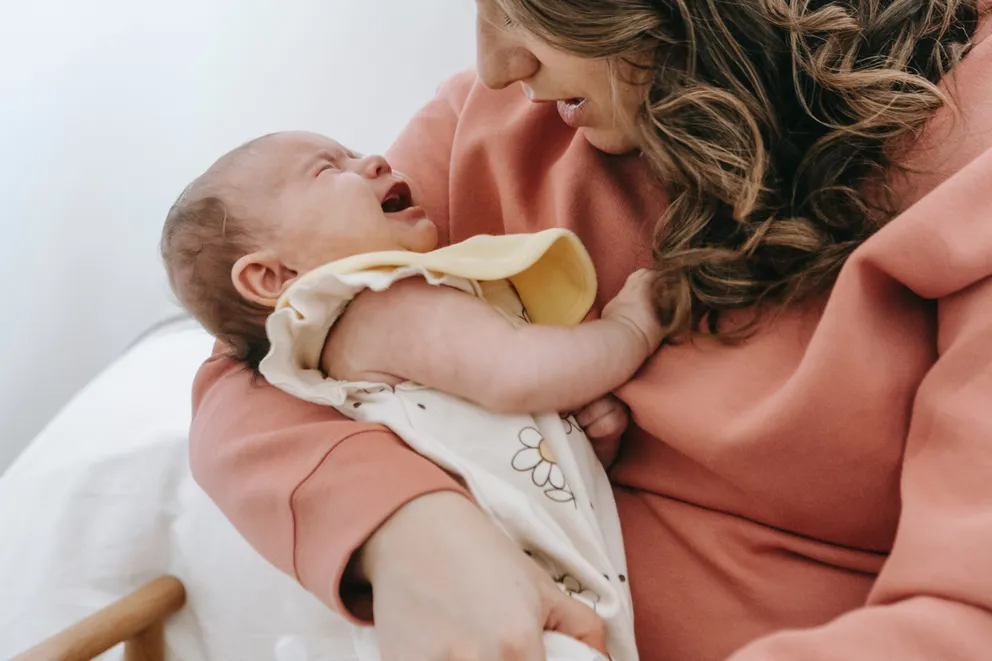 Una mujer sosteniendo a un bebé recién nacido en brazos. | Foto: Pexels