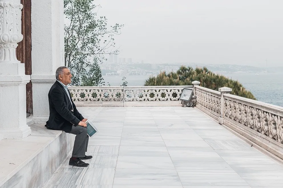 Hombre sentado en una terraza mirando hacia el horizonte. │Foto: Pixabay