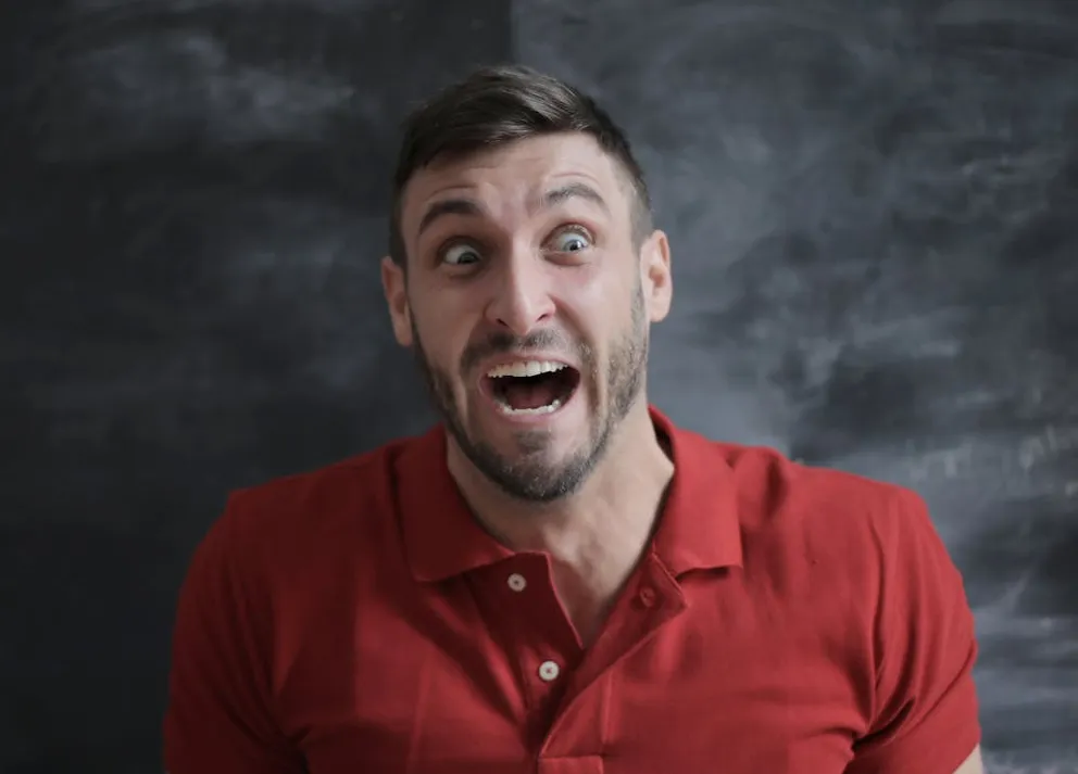 Shocked face of a man in red button up shirt. | Photo: Pexels
