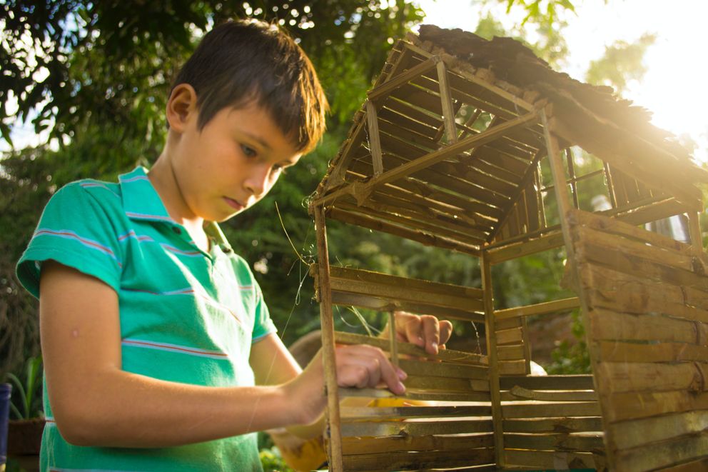 Un niño construyendo un pequeño granero de madera. | Foto: Pexels