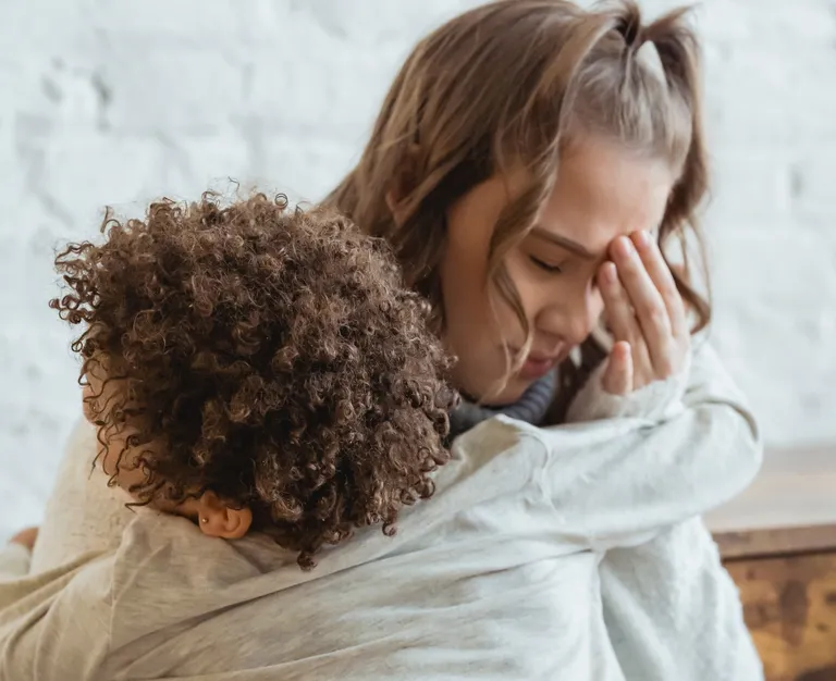 Una mujer con rostro angustiado abrazando a una niña. | Foto: Pexels