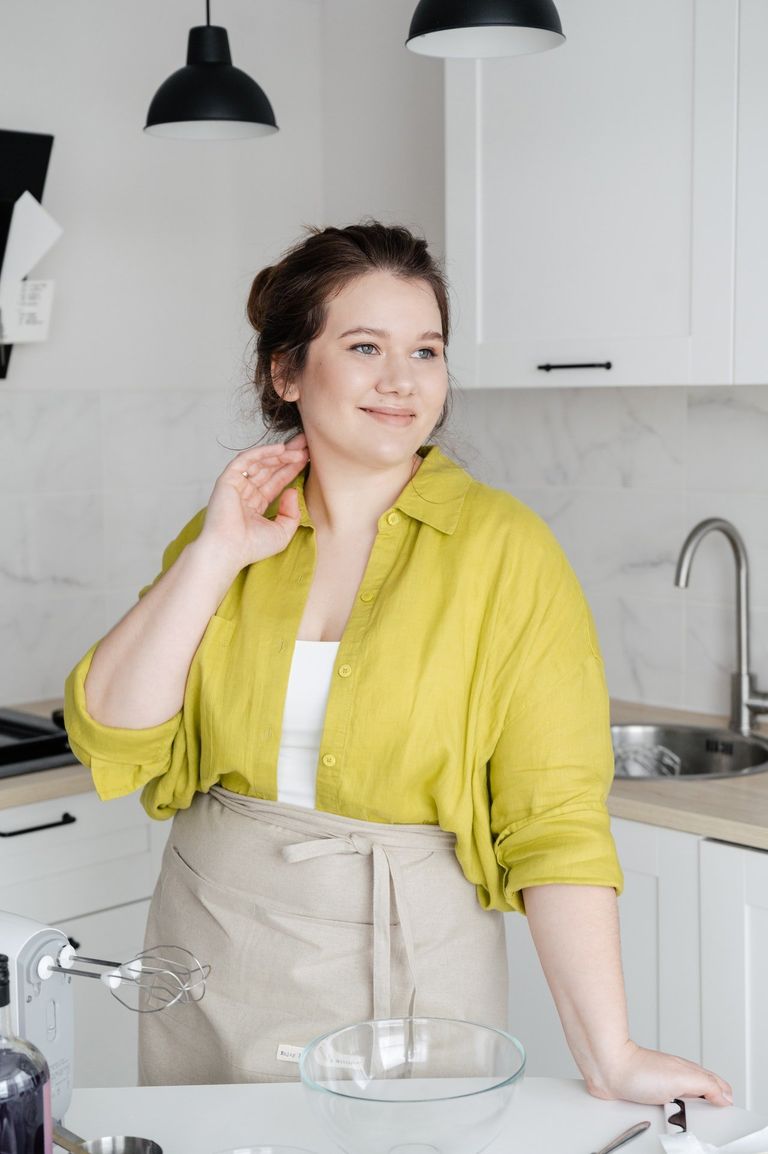 Una mujer sonriente frente a un mesón en su cocina. | Foto: Pexels