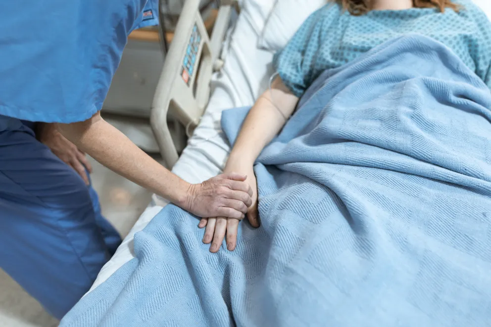 Una mujer recostada en una cama de hospital con una enfermera a su lado. | Foto: Pexels