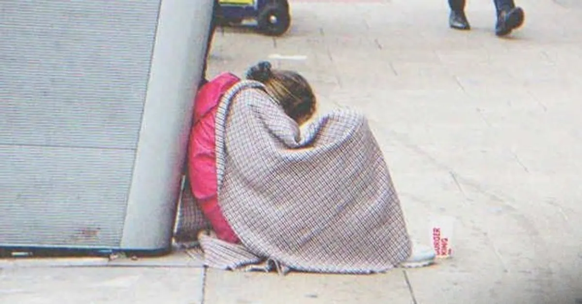 Joven sentada en el suelo cubierta con una cobija en la calle. | Foto: Shutterstock