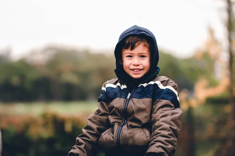 Niño vistiendo una chaqueta y sonriendo. | Foto: Pexels