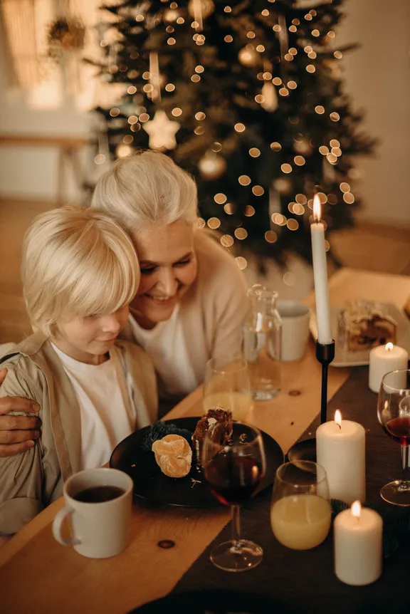 Una abuela y su nieto sentados frente a una mesa con comida. | Foto: Pexels