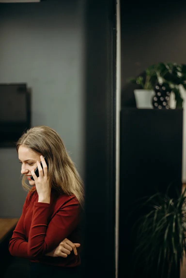 Una mujer sonriendo mientras habla a través de un teléfono celular. | Foto: Pexels
