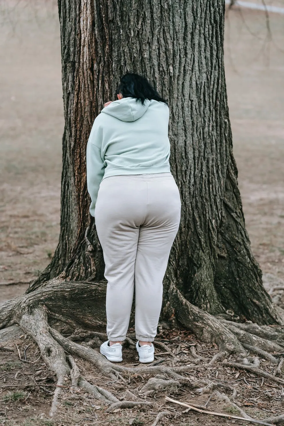 Joven llorando apoyada en un árbol. │Foto: Pexels