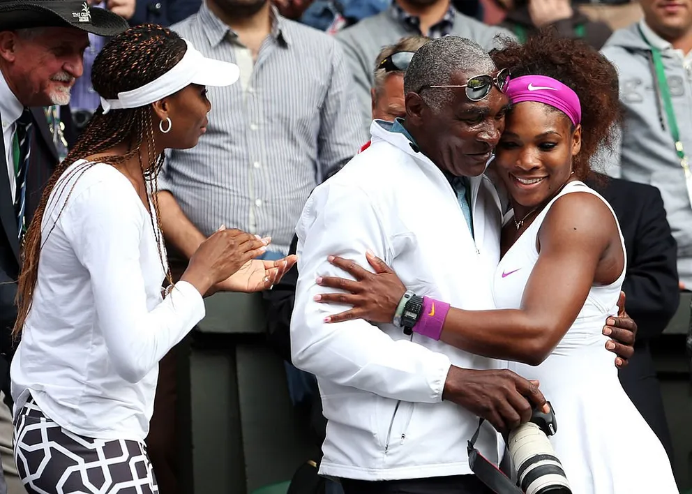 Venus Williams regarde son père Richard qui serre Serena dans ses bras après la finale du simple dames aux Championnats de tennis sur gazon de Wimbledon, le 7 juillet 2012, à Londres, en Angleterre. | Photo : Getty Images
