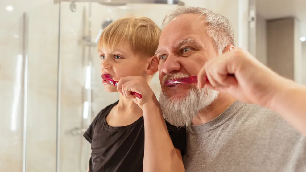 Un hombre mayor y un niño cepillándose los dientes. | Foto: Pexels
