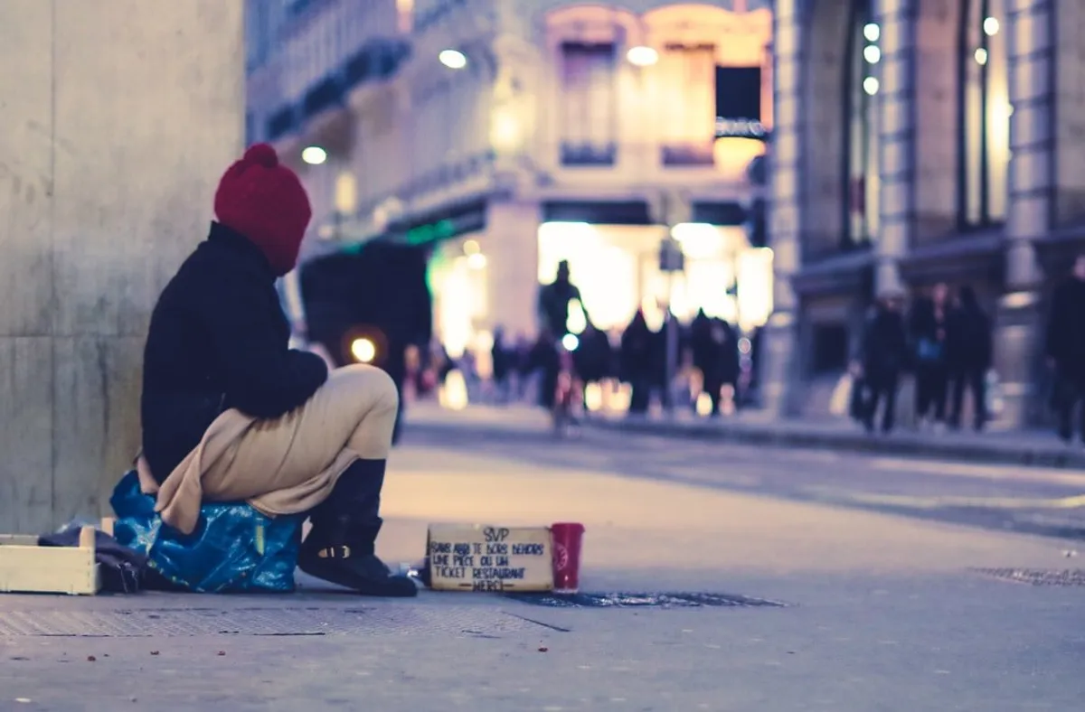 Mujer sin hogar recostada de una pared en una calle. | Foto: Shutterstock