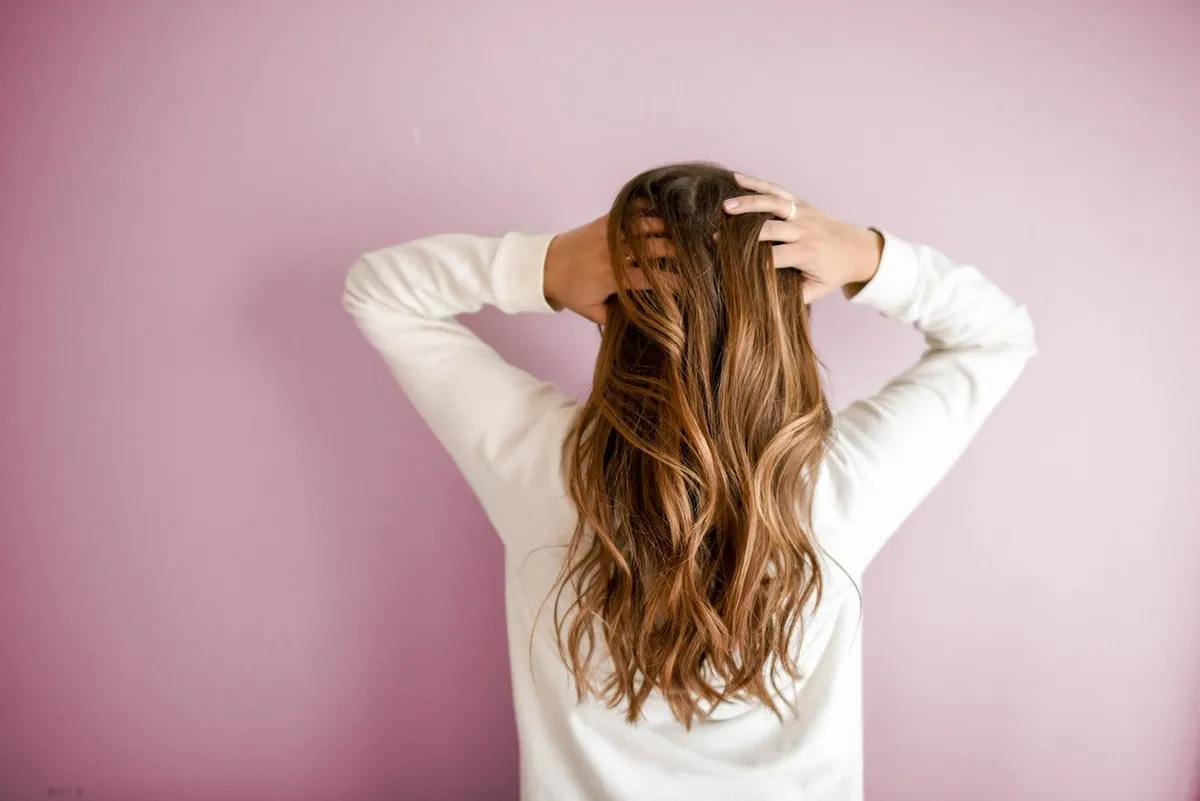 Mujer de espalda con las manos en la cabeza. | Foto: Pexels