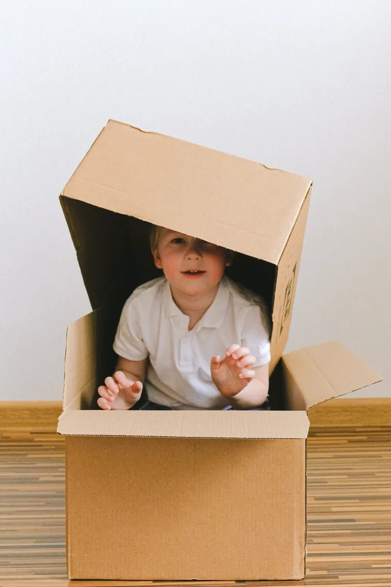 Un niño jugando dentro de dos cajas de cartón. | Foto: Pexels