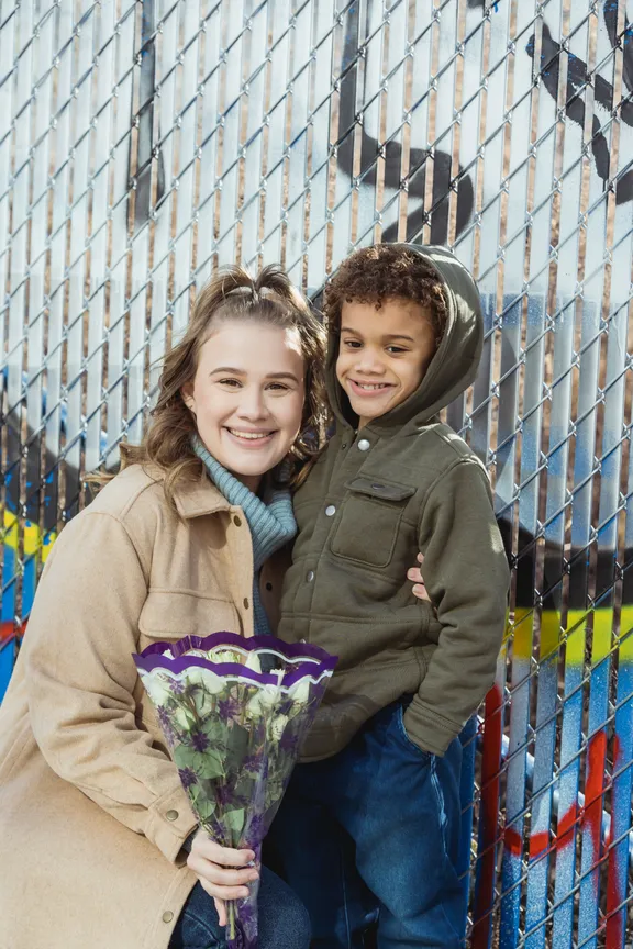 Una mujer sosteniendo un ramo de flores junto a un niño. | Foto: Pexels