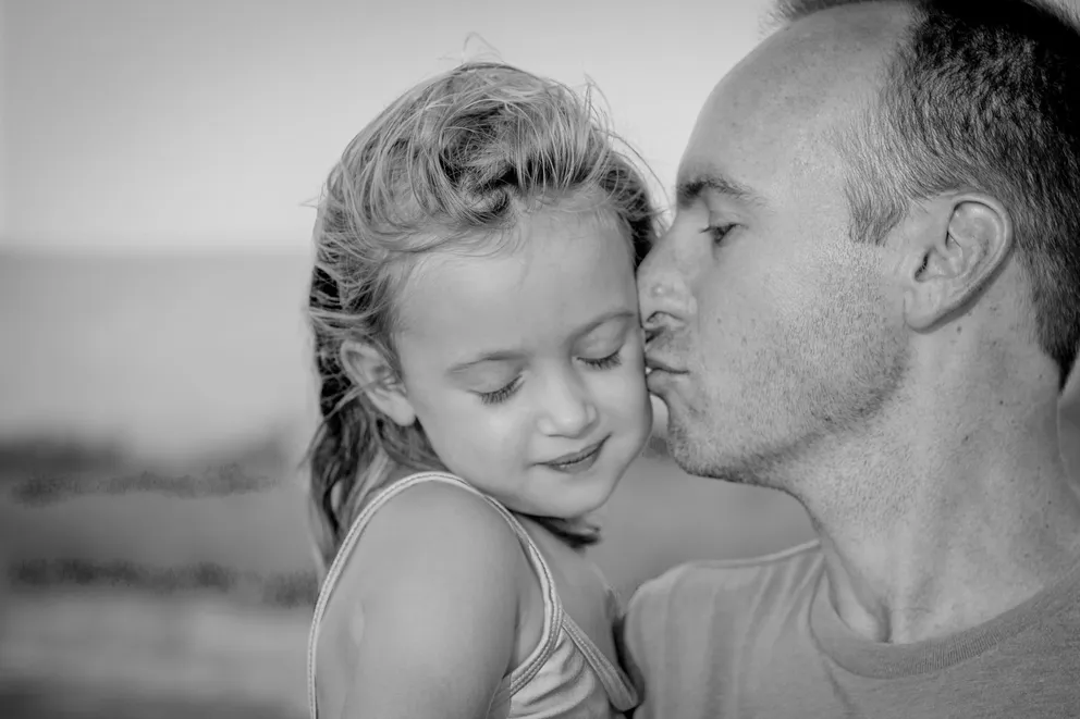 Un hombre besando en la mejilla a una niña. | Foto: Unsplash
