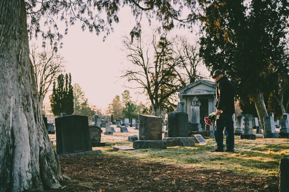 Hombre en un cementerio frente a una tumba. │Foto: Pexels / Brett Sayles