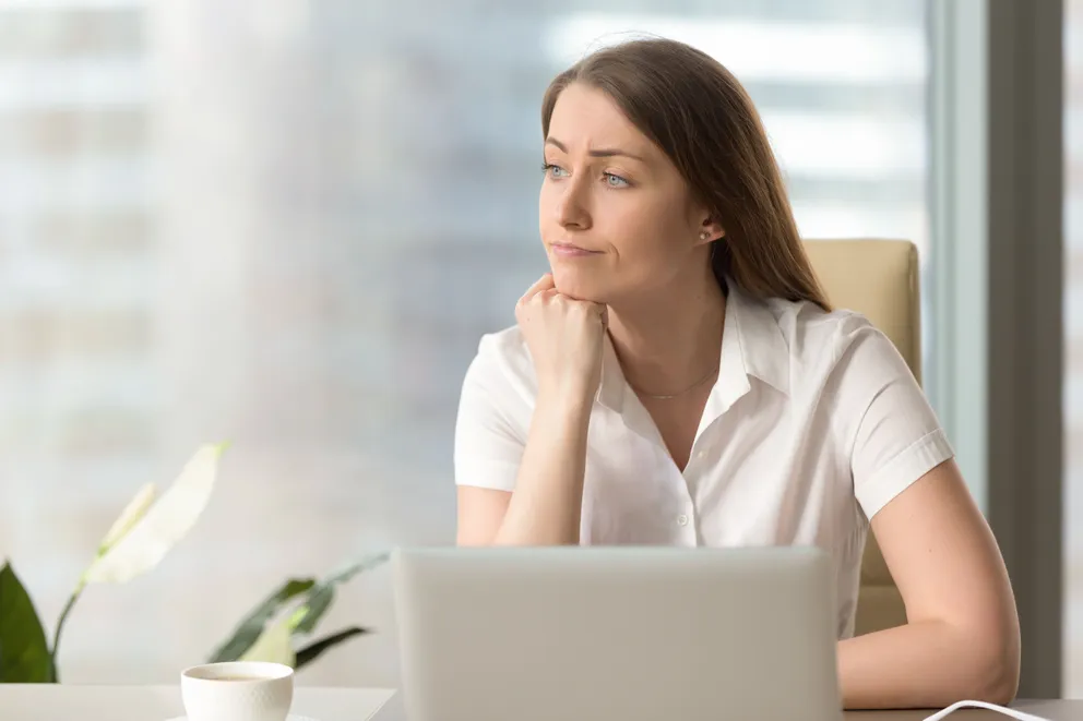 Una mujer con rostro pensativo sentada frente a una computadora. | Foto: Shutterstock