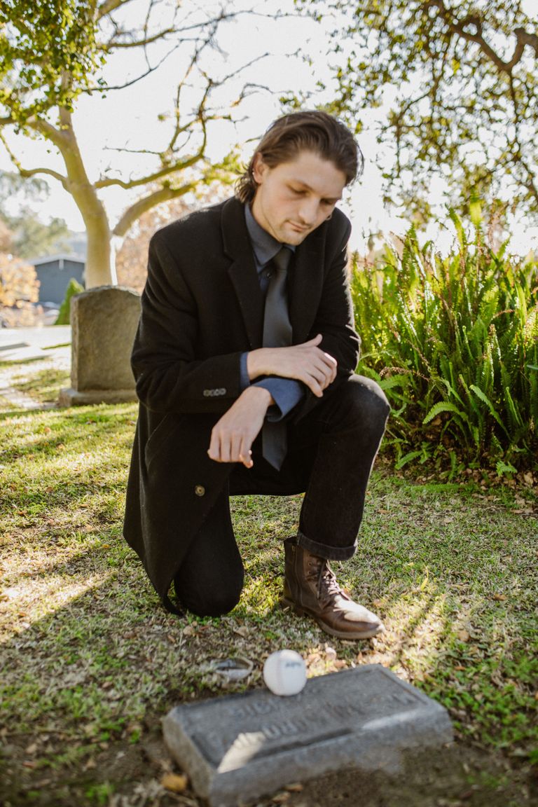 Un hombre de luto de rodillas ante una tumba. | Foto: Pexels