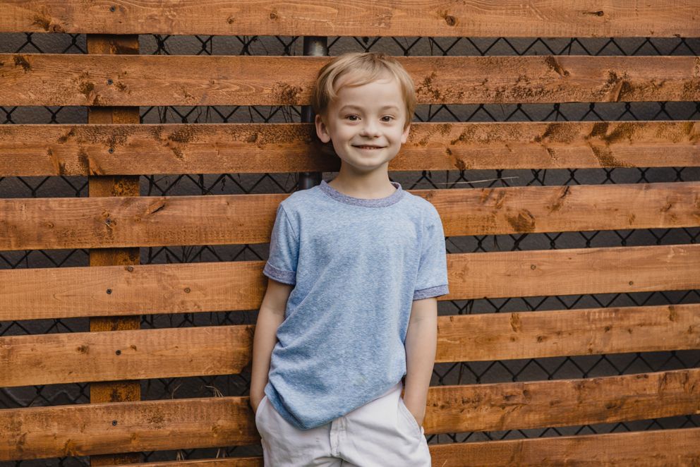 Un niño sonriente recostado de una pared. | Foto: Pexels