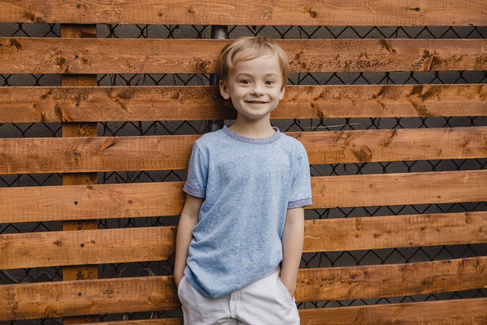 Un niño sonriente recostado de una pared. | Foto: Pexels