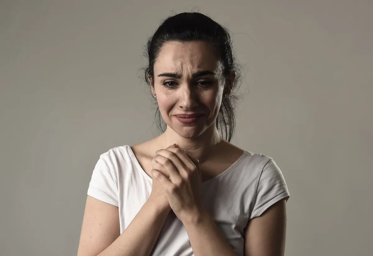 Una mujer angustiada apretando sus manos sobre su pecho. | Foto: Shutterstock