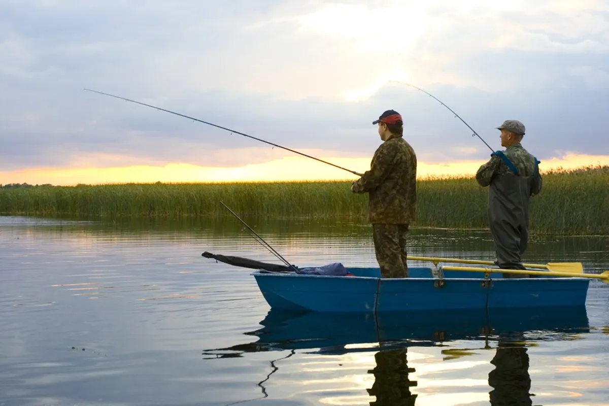 Two men on a boat fishing. | Photo: Shutterstock