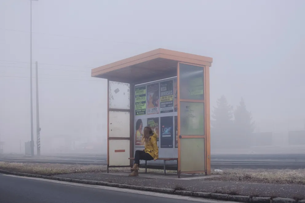 Mujer sentada en el banquillo de una parada de autobús. | Foto: Unsplash