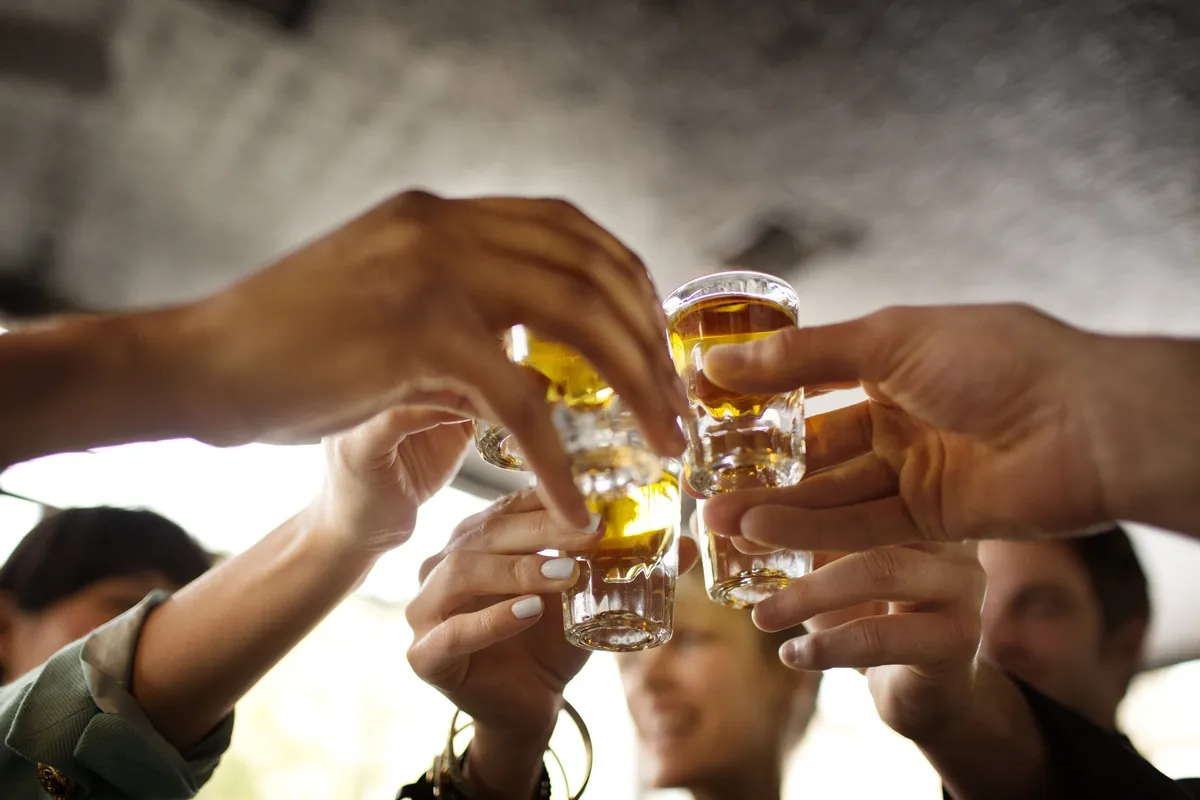 Friends toasting with shots of tequila in a bar. | Photo: Getty Images