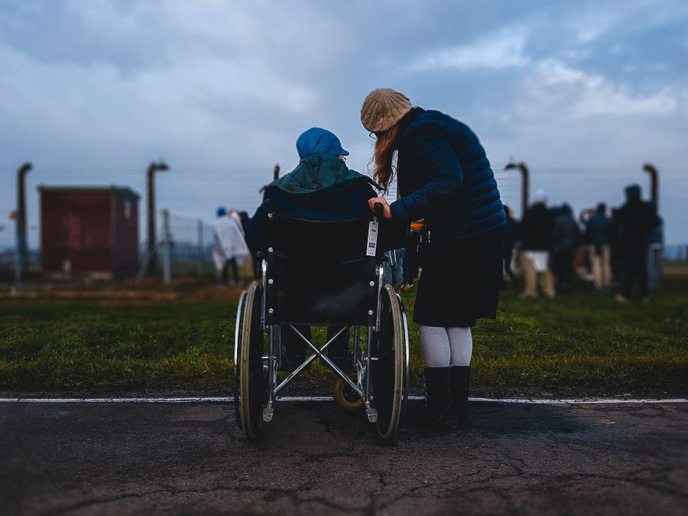 Una joven parada junto a un hombre en silla de ruedas. | Foto: Unsplash