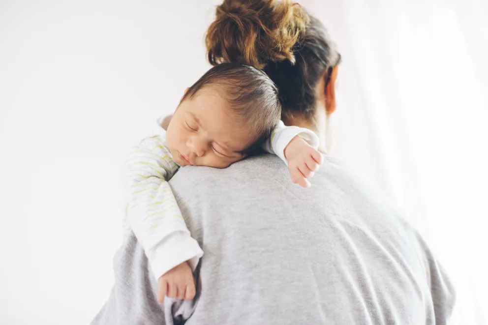 Una mujer cargando a un bebé recién nacido sobre sus hombros. | Foto: Getty Images