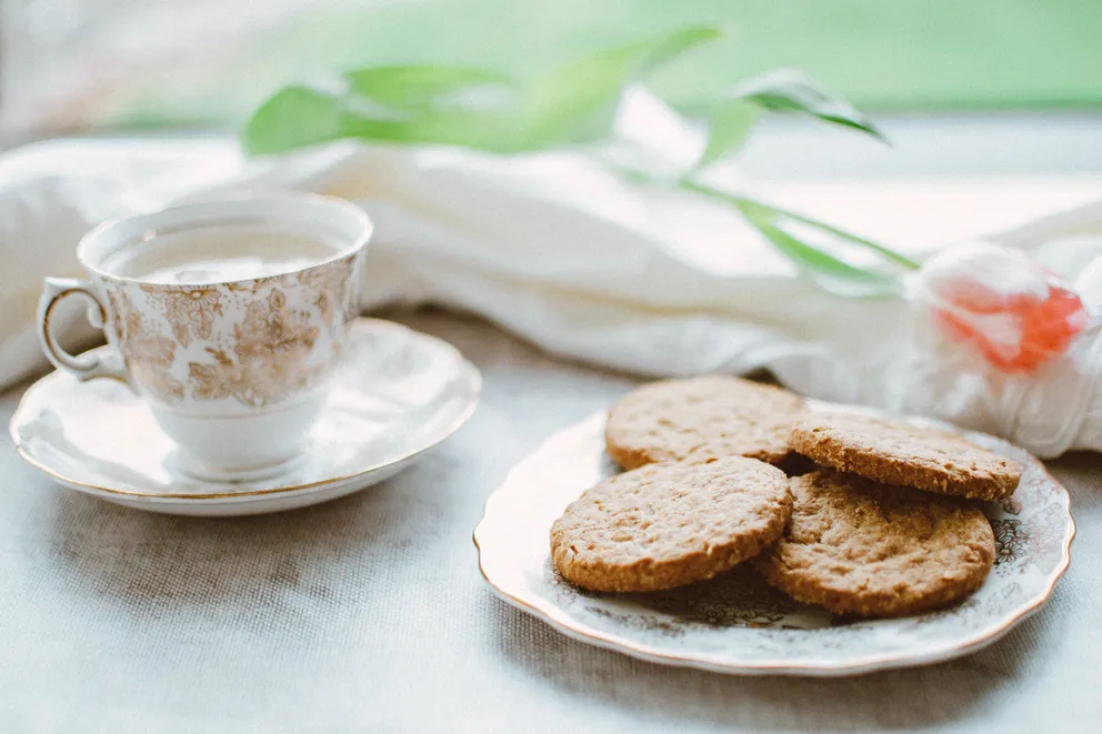 Una taza con té junto a un plato con galletas. | Foto: Pexels