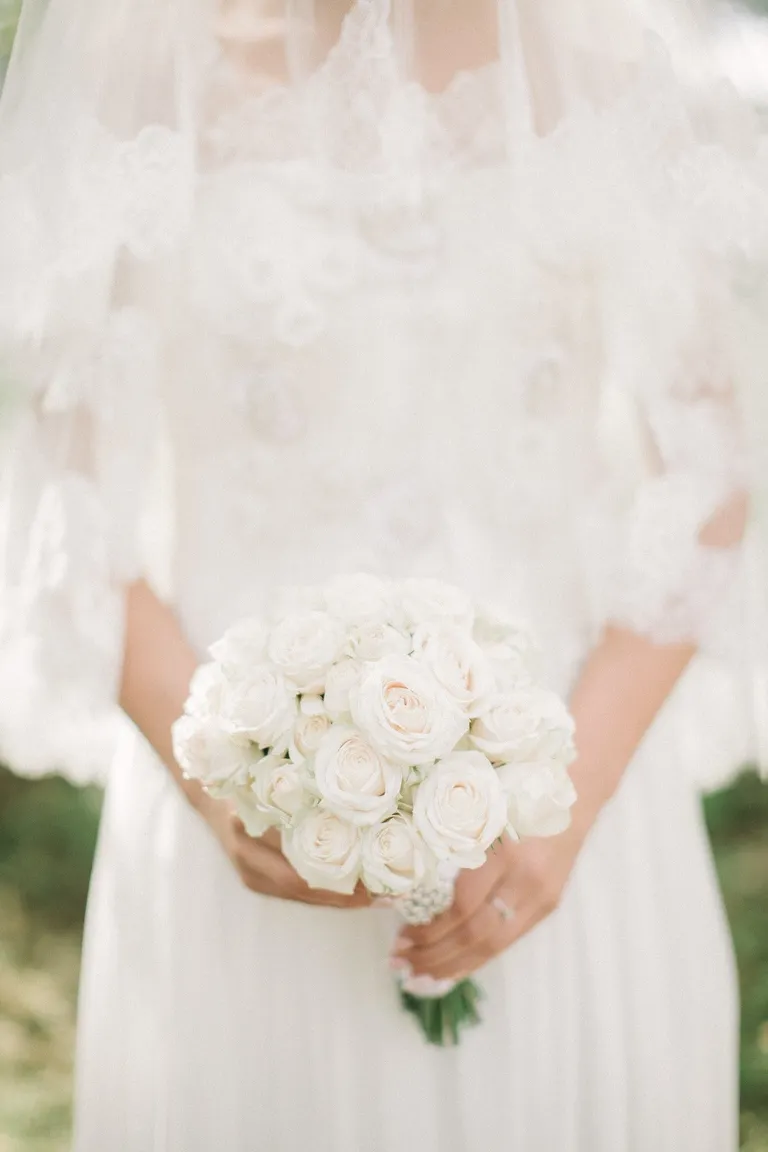 Novia usando un vestido blanco mientras sostiene un ramo de flores blancas. | Foto: Pexels