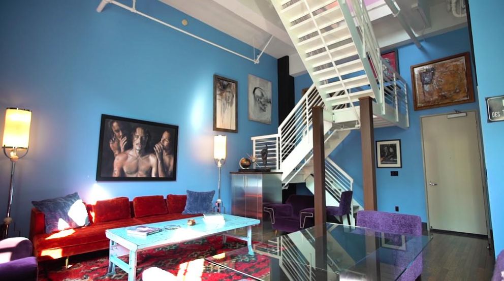 La zona del salón de Johnny Depp y Amber, de color azul brillante, con retratos colgados en la pared y una escalera blanca. | Foto: YouTube@ThePropertyCountdown