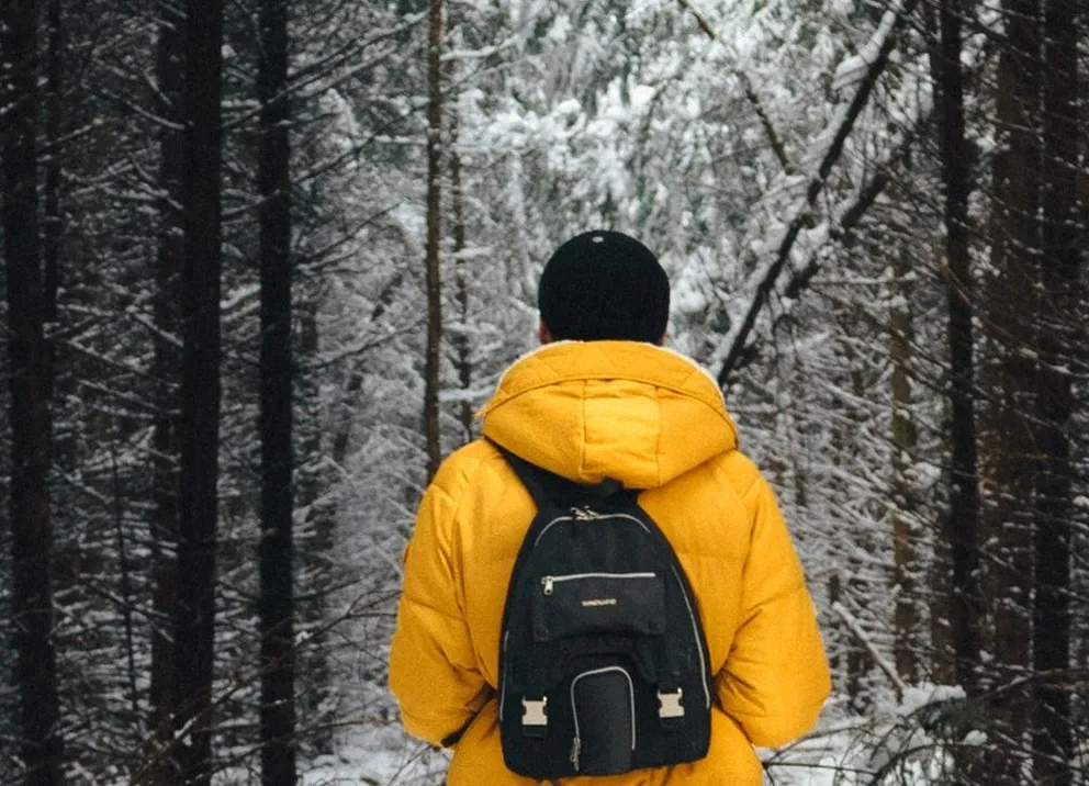 Un chico usando una sudadera con capucha mientras camina por el bosque. | Foto: Unsplash