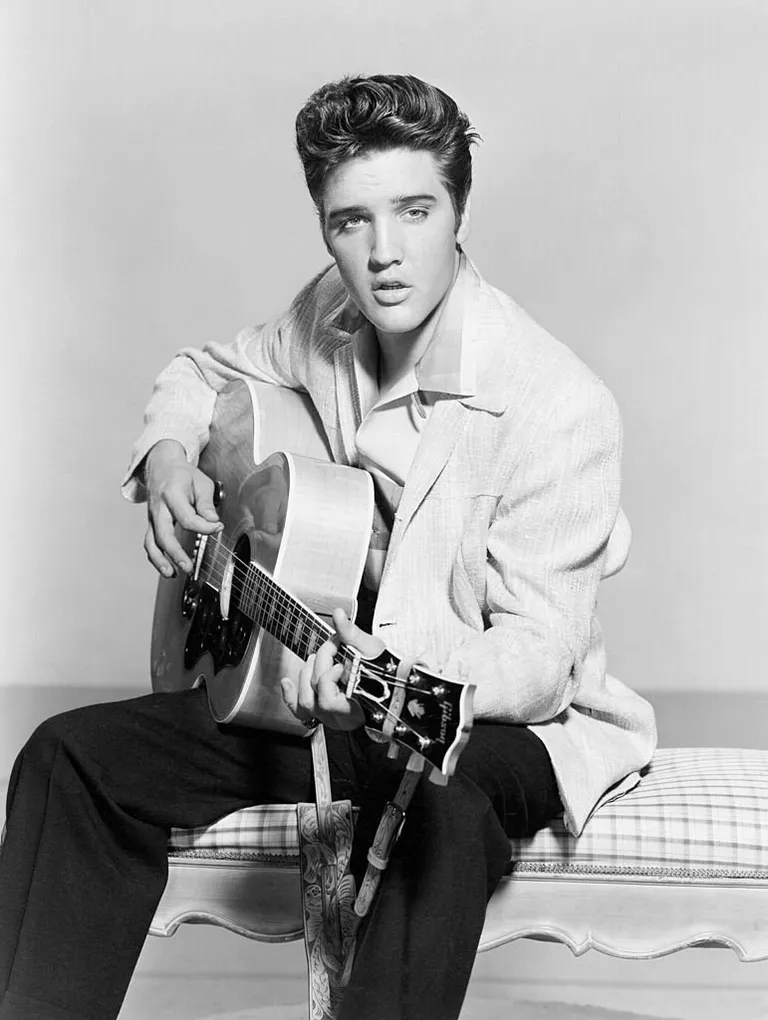 Elvis Presley gratte sa guitare acoustique dans un portrait en 1956. | Photo : Getty Images