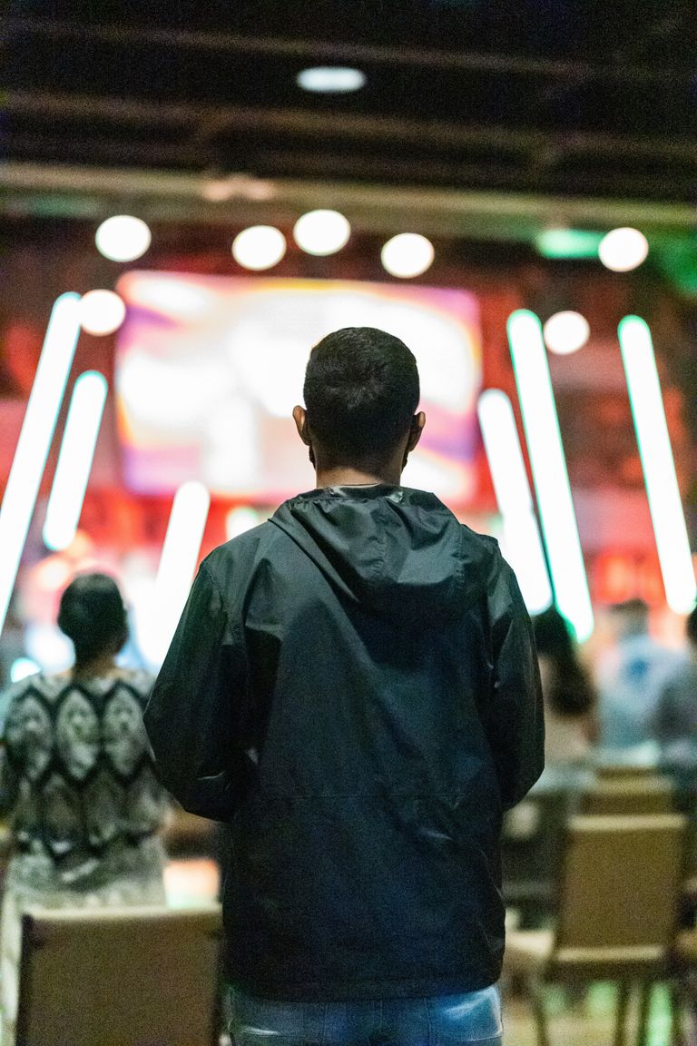 Un hombre con una chaqueta mirando hacia un escenario. | Foto: Pexels