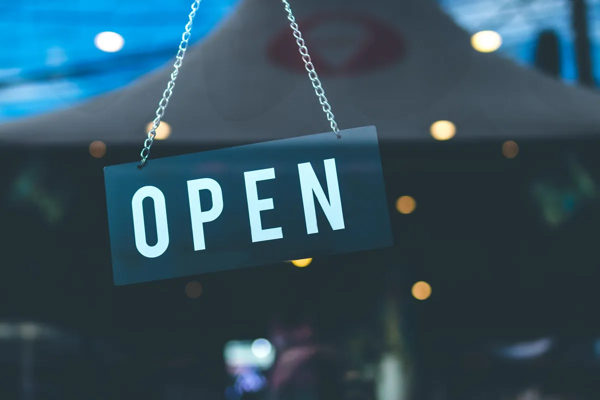 Puerta de vidrio de una tienda con un letrero de "abierto". | Foto: Pexels