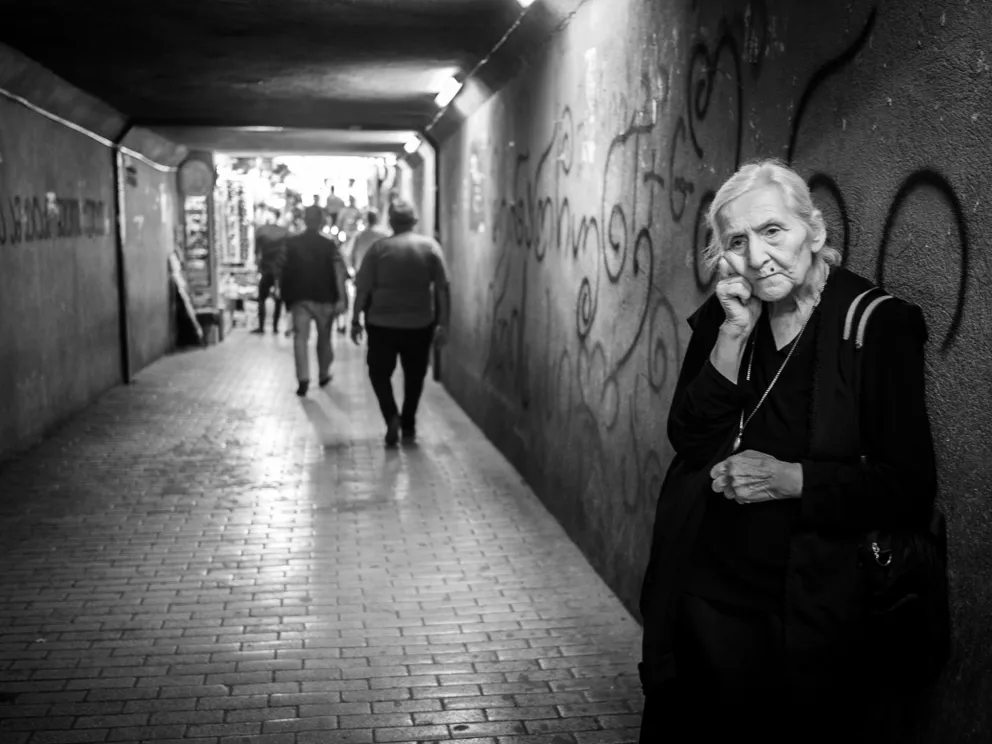 Una anciana recostada de un muro. | Foto: Pexels